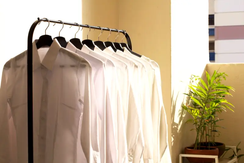 Camisas blancas colgadas en perchas sobre un fondo claro